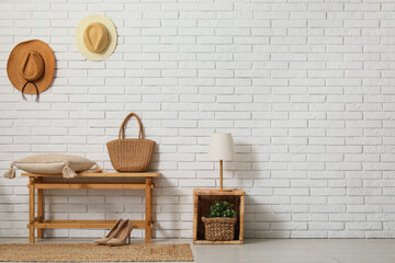 Bench with cushions and accessories near white brick wall in room