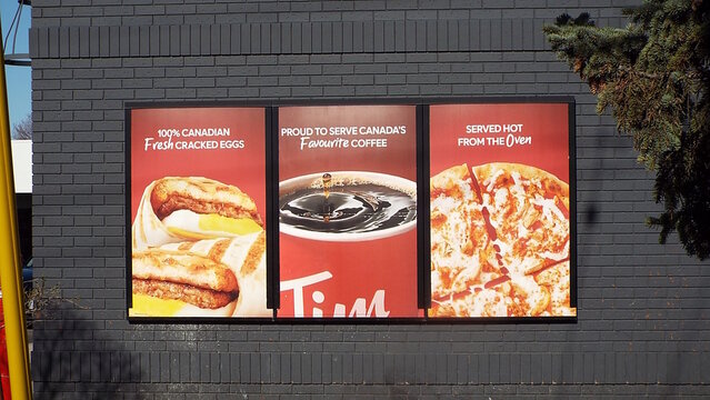 Ottawa, ON, Canada-May 25,2025: "Three Tim Hortons advertisements" on a dark brick wall at 1200 St. laurent Blvd.
