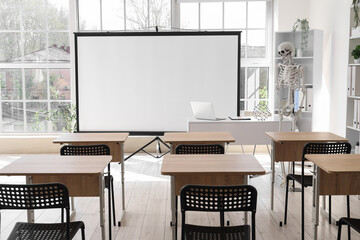Interior of light hospital conference hall with human skeleton model, modern laptop on table and...