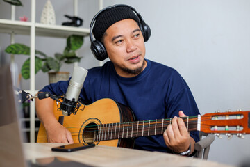 Asian Bearded Man Playing Guitar and Podcasting at Home