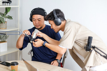 Man Reaching to Adjust Guest's Mic Angle in Podcast Studio Environment.