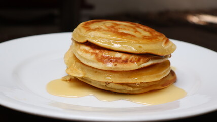 Stack of fluffy golden pancakes drizzled with maple syrup