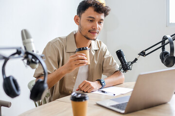 Young Asian Guy Recording Podcast While Drinking Coffee in Broadcasting Studio