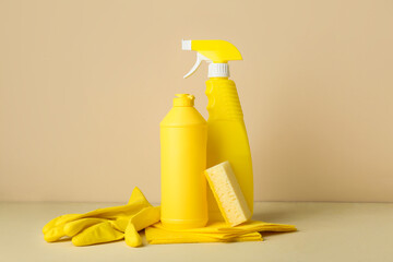 Set of cleaning supplies and bottles of detergent on beige background