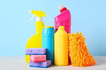 Set of cleaning supplies and bottles of detergent on blue background, closeup
