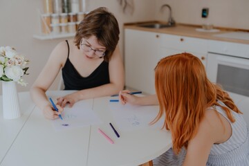 A 13-year-old teenage girl and her mother are drawing and playing together. They enjoy creative...