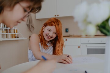 A 13-year-old teenage girl and her mother are drawing and playing together. They enjoy creative...