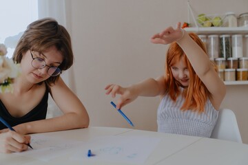 A 13-year-old teenage girl and her mother are drawing and playing together. They enjoy creative...