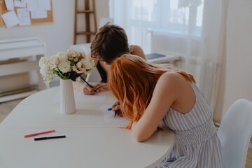 A 13-year-old teenage girl and her mother are drawing and playing together. They enjoy creative...