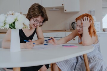 A 13-year-old teenage girl and her mother are drawing and playing together. They enjoy creative...