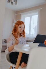 A 13-year-old teenage girl is having breakfast while playing on her tablet. She enjoys her morning...