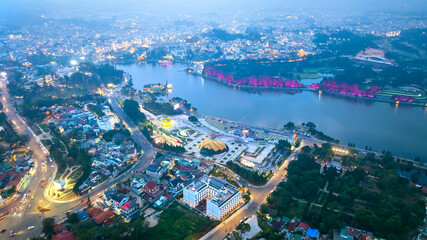 Obraz premium Aerial view of Sunflower Building at night in Da Lat City. Tourist city in developed Vietnam. Center Square of Da Lat city with Xuan Huong lake.
