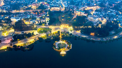 Obraz premium Aerial view of Sunflower Building at night in Da Lat City. Tourist city in developed Vietnam. Center Square of Da Lat city with Xuan Huong lake.