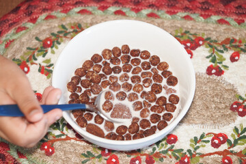 Child enjoying cereal with milk in a cozy setting