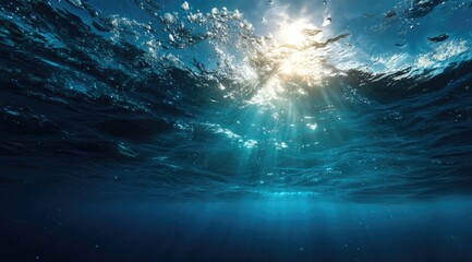 Underwater scene showing sunbeams piercing deep blue water, creating a dramatic contrast of light and shadow.  Ripples and subtle particulate matter visible