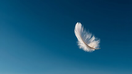a single, white feather floating against a vibrant blue sky.