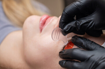 Caucasian woman undergoing eyelash lamination procedure. 