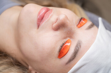 Caucasian woman undergoing eyelash lamination procedure. 