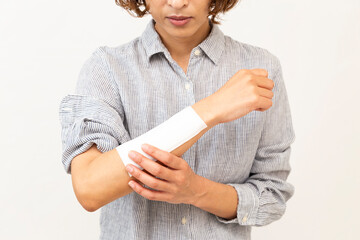 腕に貼った湿布を気にする女性