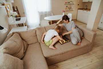 A loving mother and her son play chess together at home, enjoying a fun and educational moment. The...