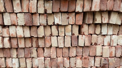Stacked red bricks display varying shades and textures in a simple, eyelevel brickwork pattern