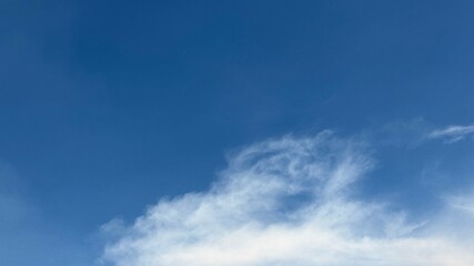 White cloud edges softly meet the crisp blue horizon in the clear sky