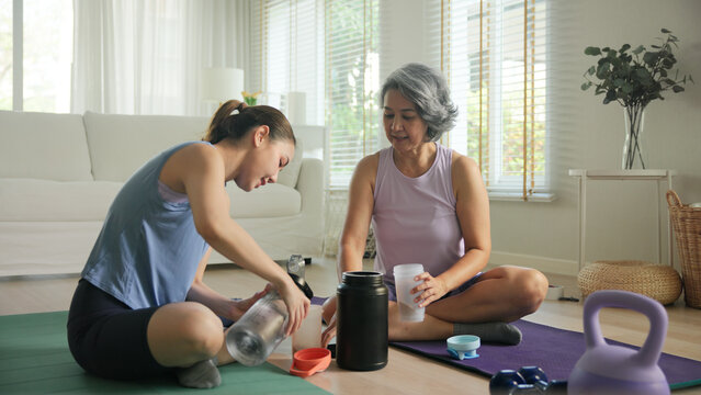 Young adult child active mature middle age old mum drink whey protein shake bottle diet food after home workout. Love health care older aged mom asia elder people happy relax sport protect aging life.