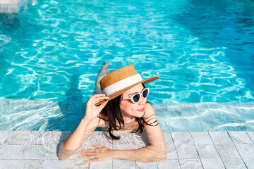 Young happy woman traveler relaxing and enjoying a tropical resort pool while traveling for summer vacation, Travel concept