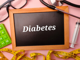 Wooden board and doctor's equipment with the word Diabetes on a pink background