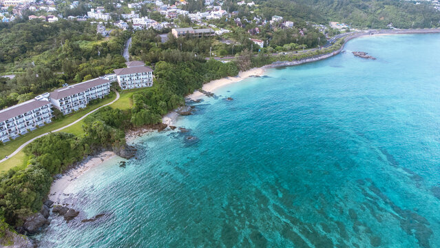 The serene seascape of Okinawa showcases crystal-clear waters, exposed rocky formations, and gentle waves lapping against the shore.