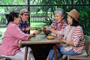 Group of elderly Asian friends enjoy Tea time in cafe with cake, talking, luaghing enjoy free time holiday after retirement, senior pension females spend time together in coffee shop meeting lifestyle