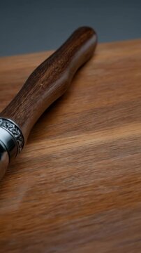 Close-up of vintage metal and wood muddler against a wooden surface, showcasing craftsmanship and materials, useful for bartenders