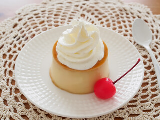 白い皿の上のクリームとサクランボを添えた手作りプリン