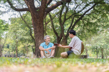 senior father and young adult son spend holiday time having picnic together,playing guitar,resting,conversation,concept family lifestyle,bonding,relationship