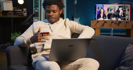 Fototapeta premium Responsible male adult does his taxes with the credit card at home, entering numbers online on laptop and confirming the payment via web. Man organizing documents and financial details. Camera B.