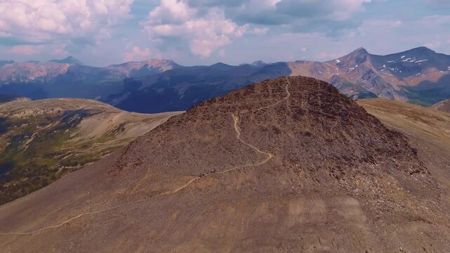 Drone orbits hikers as they descend a trail from a mountain summit in the Purcell Mountains, Golden, BC.
