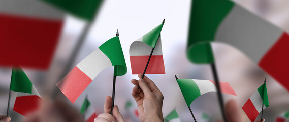 Italy flags in their hands on a blurred urban background