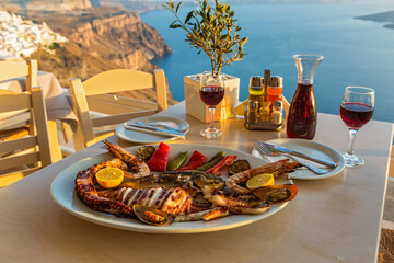 Delicious Greek seafood platter with grilled octopus & wine overlooking Santorini's Aegean Sea....