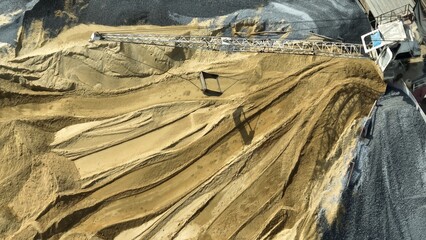 A crane-mounted system extends over sorted aggregate piles, showcasing the mechanical precision...