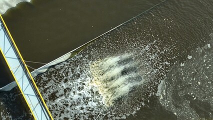 A paddlewheel aerator churns murky wastewater, boosting oxygenation to support microbial breakdown of contaminants in industrial treatment ponds.
