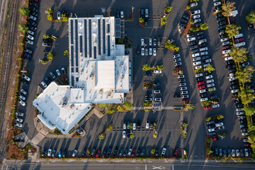 Aerial drone top-down view of a busy and full parking lot at a large car dealership in Beaverton, Oregon, with many parked cars and clearly marked driving lanes	
