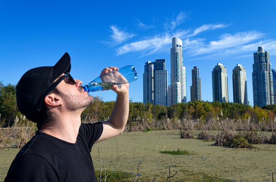 Persona hidrat&aacute;ndose con agua al aire libre ante calor extremo y sol sofocante de verano. 