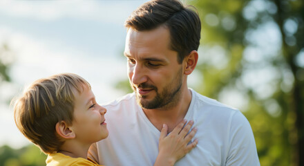 Fototapeta premium Father and son sharing loving moment with child's hand on father's chest outdoors. Tender paternal bonding and trust. Father's Day greeting cards and family wellness promotions