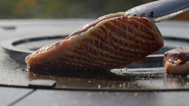 slowmotion shot of a chef checking the sear on the topside of a steak on a BBQ