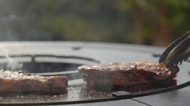slowmotion of a sirloin steak being flipped to brown both sides on a BBQ