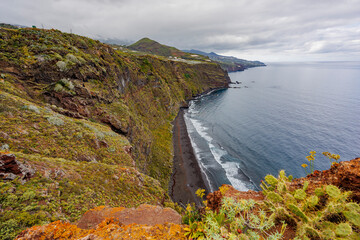 Dramatic geological formations along a rugged coastline with ocean views, showing volcanic layers, erosion textures and natural detail.