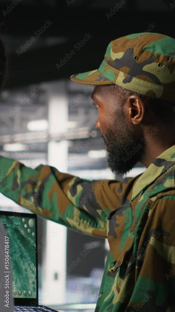 Poster vertical video military experts in data center reviewing drone surveillance feed on laptop screen. a