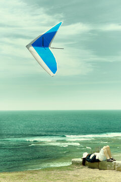 Lady resting with hang glider above on a beautiful day