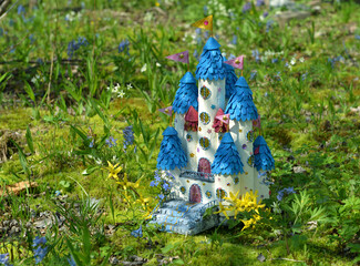 Cute fairy doll house or castle with spring flowers outside in the garden. Lovely miniature for greeting cards, wedding or birthday, real estate, downsizing, home ownership. Vintage spring background