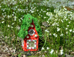Cute fairy doll house with spring flowers outside in the garden. Lovely miniature for greeting cards, wedding or birthday concept, real estate, downsizing, home ownership. Vintage spring background
